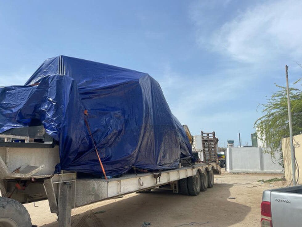 Heavy cargo under tarpaulin on a low-bed trailer